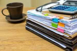 stack of folders and documents on office desk with coffee